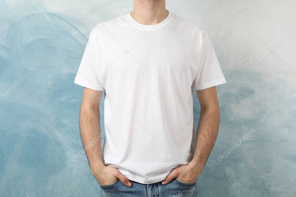 Men in blank white t-shirt against blue background, space for te