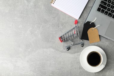 Composition with small shopping cart, laptop and cup of coffee o