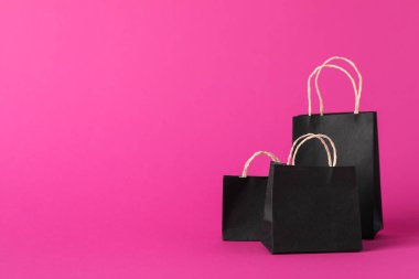 Small paper bags on pink background, space for text