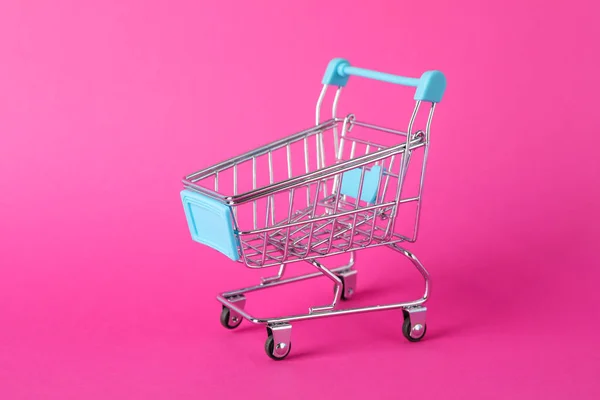 Pequeño carrito de compras sobre fondo rosa, espacio para texto —  Fotos de Stock
