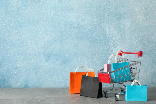 Small shopping cart and paper bags on grey background, copy spac — Stock Fotó