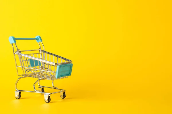 Small shopping cart on yellow background, space for text — ストック写真