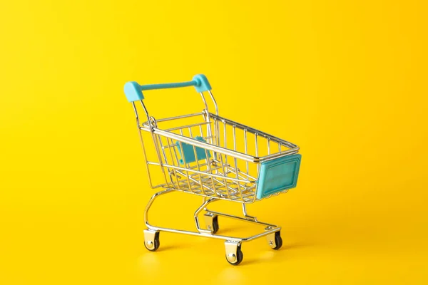 Small shopping cart on yellow background, space for text — ストック写真