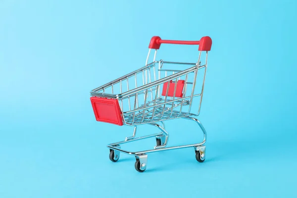 Small shopping cart on blue background, space for text — ストック写真