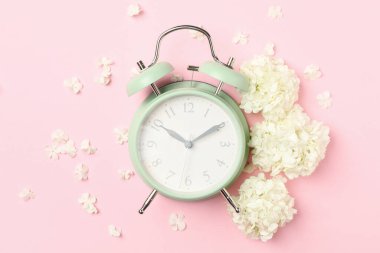Çalar saat ve pembe arka planda güzel ortanca çiçekleri