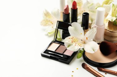 Farklı makyaj malzemeleri ve beyaz arka planda çiçekler. Kadın aksesuarları