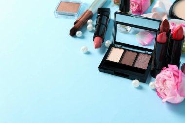 Farklı makyaj malzemeleri ve mavi arka planda çiçekler. Kadın aksesuarları