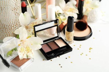 Farklı makyaj malzemeleri ve beyaz arka planda çiçekler. Kadın aksesuarları