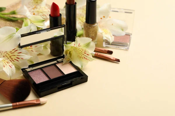 Different makeup cosmetics and flowers on beige background. Female accessories