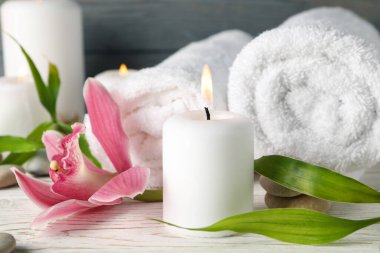 Ahşap masa üzerinde mumlar, havlular, taşlar ve orkideler olan kompozisyon. Zen kavramı