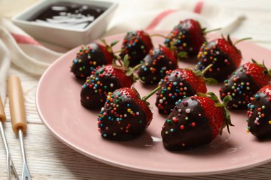 Çikolatalı fondü. Beyaz ahşap arka planda çikolatalı çilek