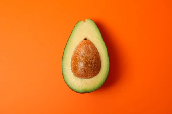 Die Hälfte Der Frischen Avocado Auf Orangefarbenem Hintergrund Nahaufnahme — Stockfoto