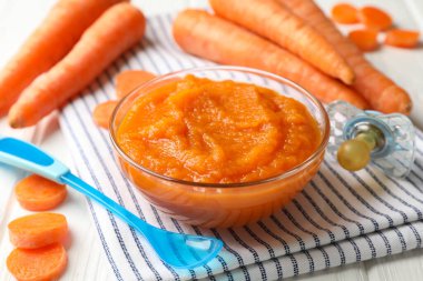 Beyaz ahşap zemin üzerinde havuç püresi olan kompozisyon. Bebek maması.