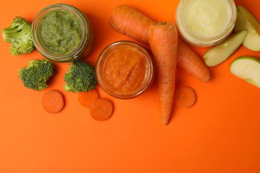 Turuncu arka planda sebze püresi olan kompozisyon. Bebek maması.
