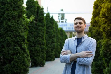 Üniversiteye karşı elleri katlanmış genç bir adam. Çalış