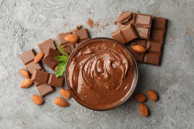 Gri arka planda çikolata ve çikolata parçaları olan kase