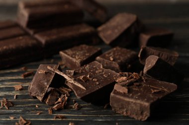 Tahta arka planda çikolata parçaları, yakın plan.