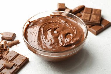 Beyaz arka planda çikolata ve çikolata parçaları olan bir kase.