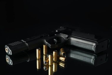 Siyah arka plana karşı ayna masasında tabanca ve mermiler