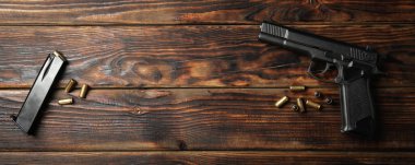 Pistol, bullets and magazine on wooden background clipart