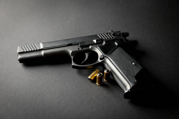 Pistol and traumatic bullets on black background. Self defense weapon