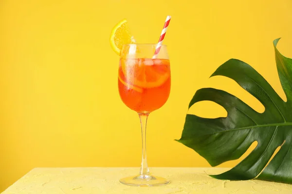 黄色の背景にアペロールスプリッツカクテルとヤシの葉 夏の飲み物 — ストック写真