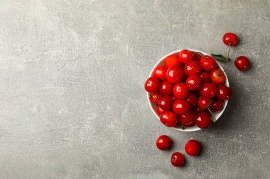 Gri arka planda kırmızı kirazlı kase, üst görünüm