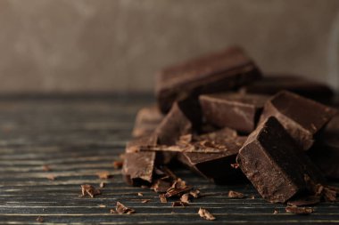 Tahta arka planda çikolata parçaları, yakın plan.
