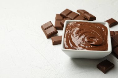 Beyaz arka planda çikolata ve çikolata parçaları olan bir kase.