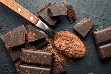 Lezzetli çikolata ve siyah arka planda toz olan kaşık.