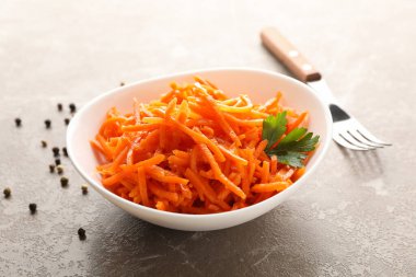 Çatal ve kâse, gri arka planda havuç salatası, yakın plan.