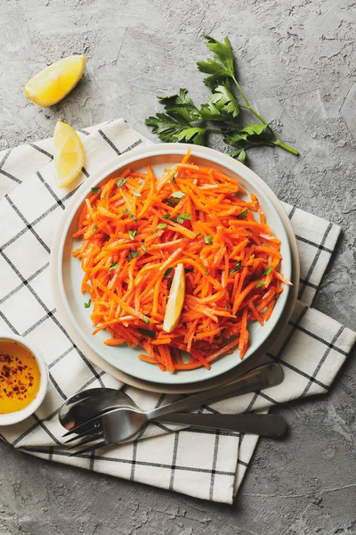 Composition with tasty carrot salad on gray background. Korean carrot