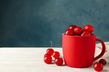 Beyaz ahşap arka planda kirazlı havlu ve bardak.