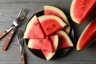 Gri ahşap masada karpuz dilimli kompozisyon. Yaz meyvesi