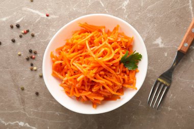 Çatal ve kâse, gri arka planda havuç salatası, üst manzara.