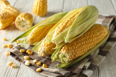 Taze çiğ mısır ve beyaz ahşap arka planda peçete.