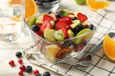 Beyaz ahşap masada bir fincan taze meyve salatasıyla kompozisyon, yakın çekim.