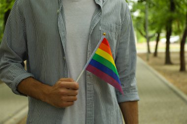 Dışarıda duran LGBT bayrağıyla genç bir adam.