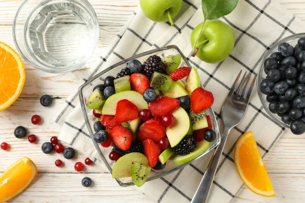 Beyaz ahşap masada taze meyve salatası ile kompozisyon, üst manzara.
