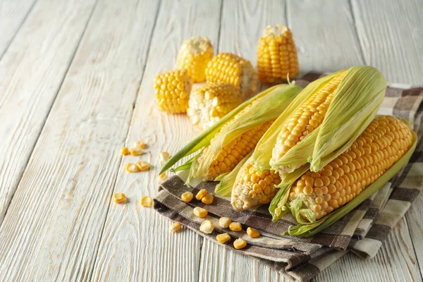 Beyaz ahşap zemin üzerinde taze çiğ mısır ve peçete, metin için boşluk