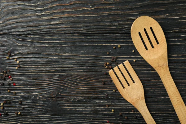 Kitchen spatula, fork and spices on wooden background