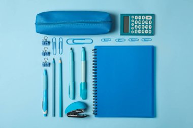 Mavi arka planda farklı okul malzemeleriyle yatıyordu.