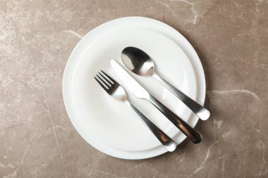 Gri arka planda çatal bıçak takımı olan tabaklar, üst görünüm