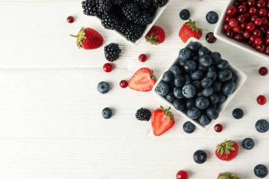 Beyaz ahşap arka planda böğürtlenli kaseler, üst manzara