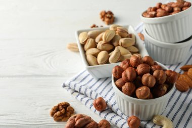 Beyaz ahşap arka planda farklı fındıklı kaseler. Vitamin yiyeceği.