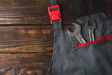 Ahşap arka planda inşaat anahtarı olan tulumlar