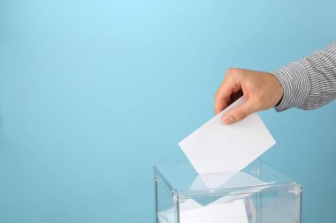 Adam oy sandığına mavi arka planda oy veriyor