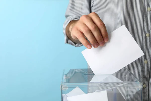 Homem Colocando Cédula Caixa Votação Contra Fundo Azul — Fotografia de Stock