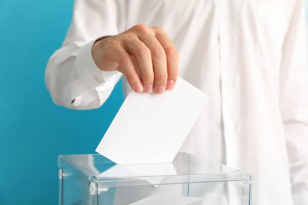 Homem Colocando Cédula Caixa Votação Contra Fundo Azul — Fotografia de Stock