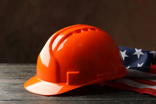 American flag and safety helmet on wooden background, close up